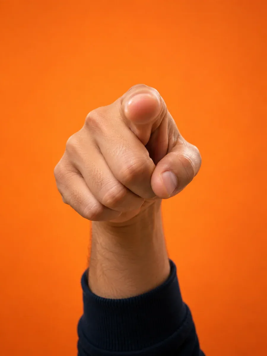 A hand pointing directly toward you against an orange backdrop
